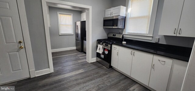 kitchen with stainless steel appliances, white cabinetry, and dark hardwood / wood-style flooring