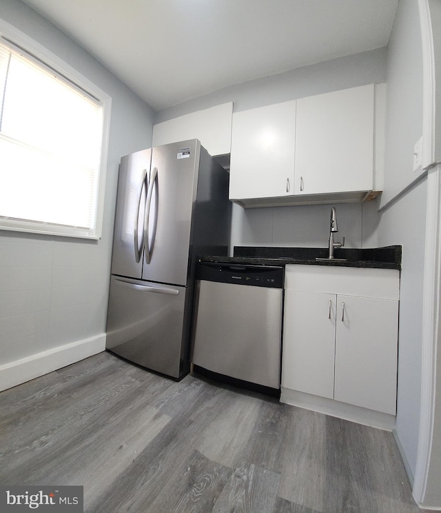 kitchen with stainless steel appliances, hardwood / wood-style flooring, sink, and white cabinets