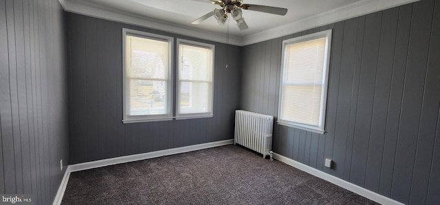 carpeted empty room featuring radiator, ornamental molding, and ceiling fan