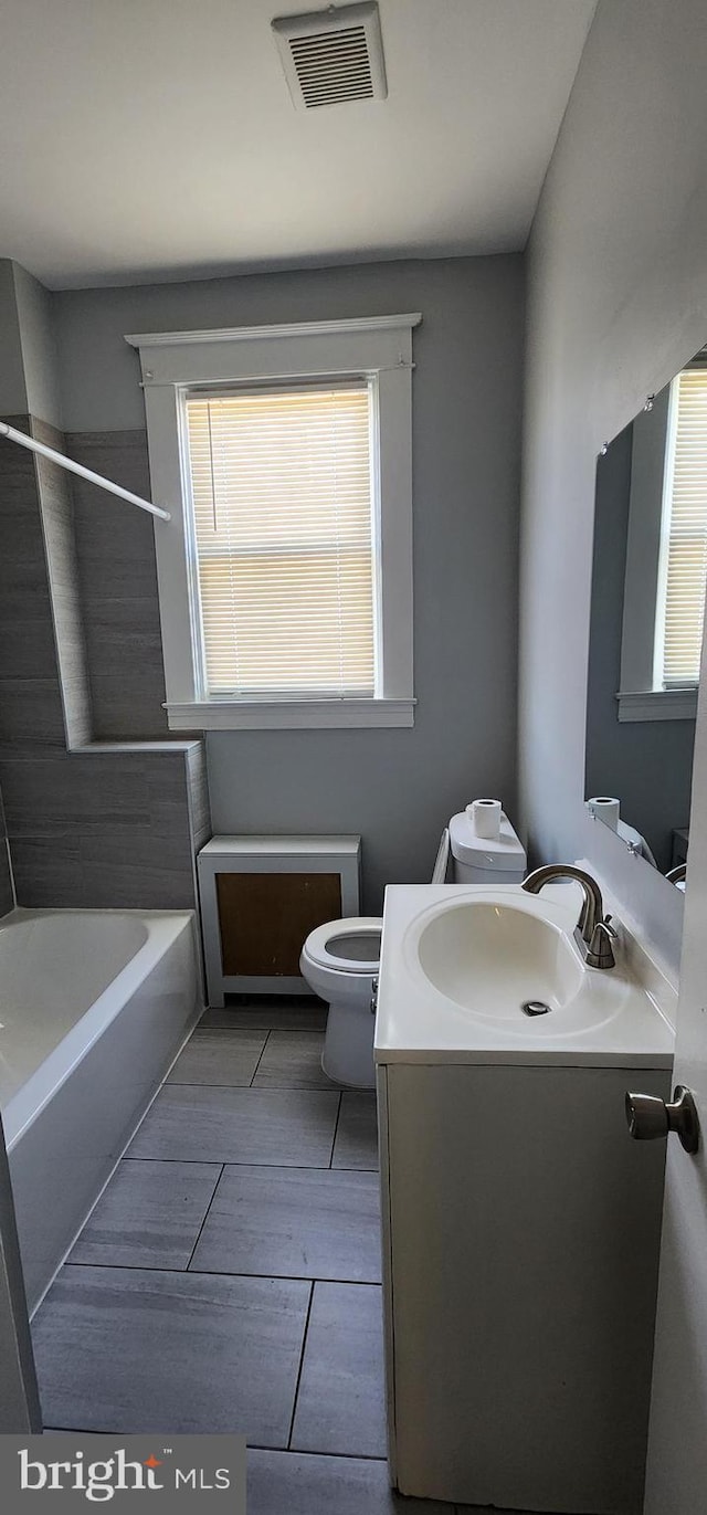 bathroom featuring vanity, a bathing tub, and toilet