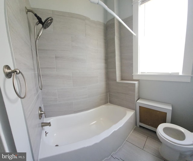 bathroom featuring tiled shower / bath, tile patterned floors, and toilet