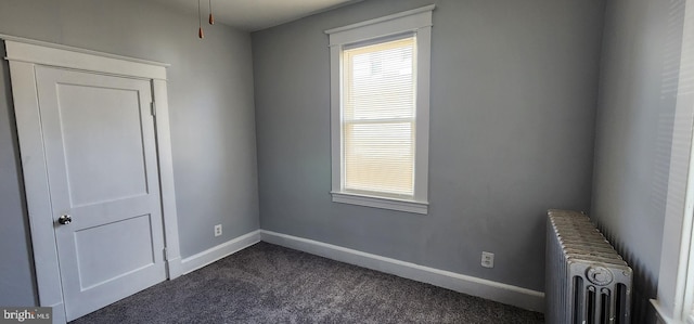 spare room featuring dark colored carpet and radiator