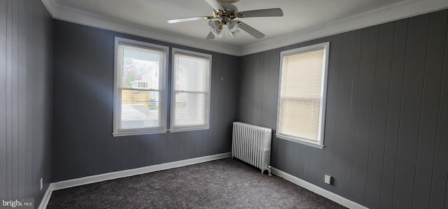 spare room with radiator heating unit, ornamental molding, ceiling fan, and dark colored carpet