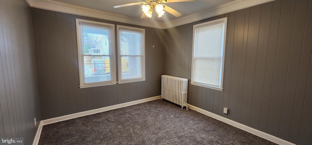 carpeted spare room with ornamental molding, radiator, and ceiling fan