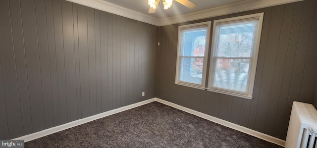 carpeted spare room featuring crown molding, ceiling fan, radiator heating unit, and wooden walls