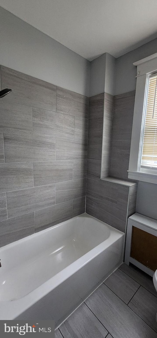 bathroom featuring toilet and tiled shower / bath