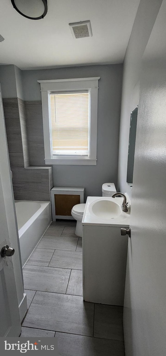 bathroom with vanity, a bathtub, and toilet