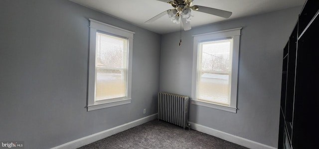 empty room with radiator, dark carpet, and ceiling fan