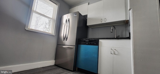 kitchen featuring dark hardwood / wood-style floors, white cabinetry, dishwasher, sink, and stainless steel fridge