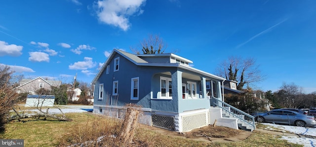 view of property exterior featuring covered porch and a lawn