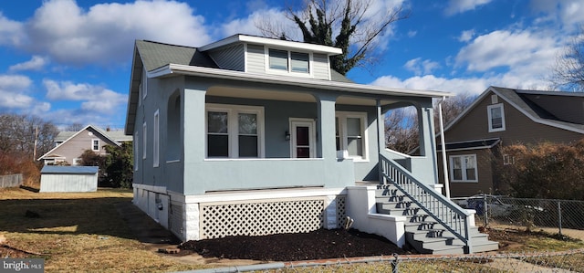 bungalow-style house featuring covered porch and a storage shed