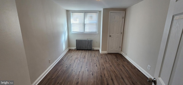 unfurnished bedroom featuring dark hardwood / wood-style flooring and radiator