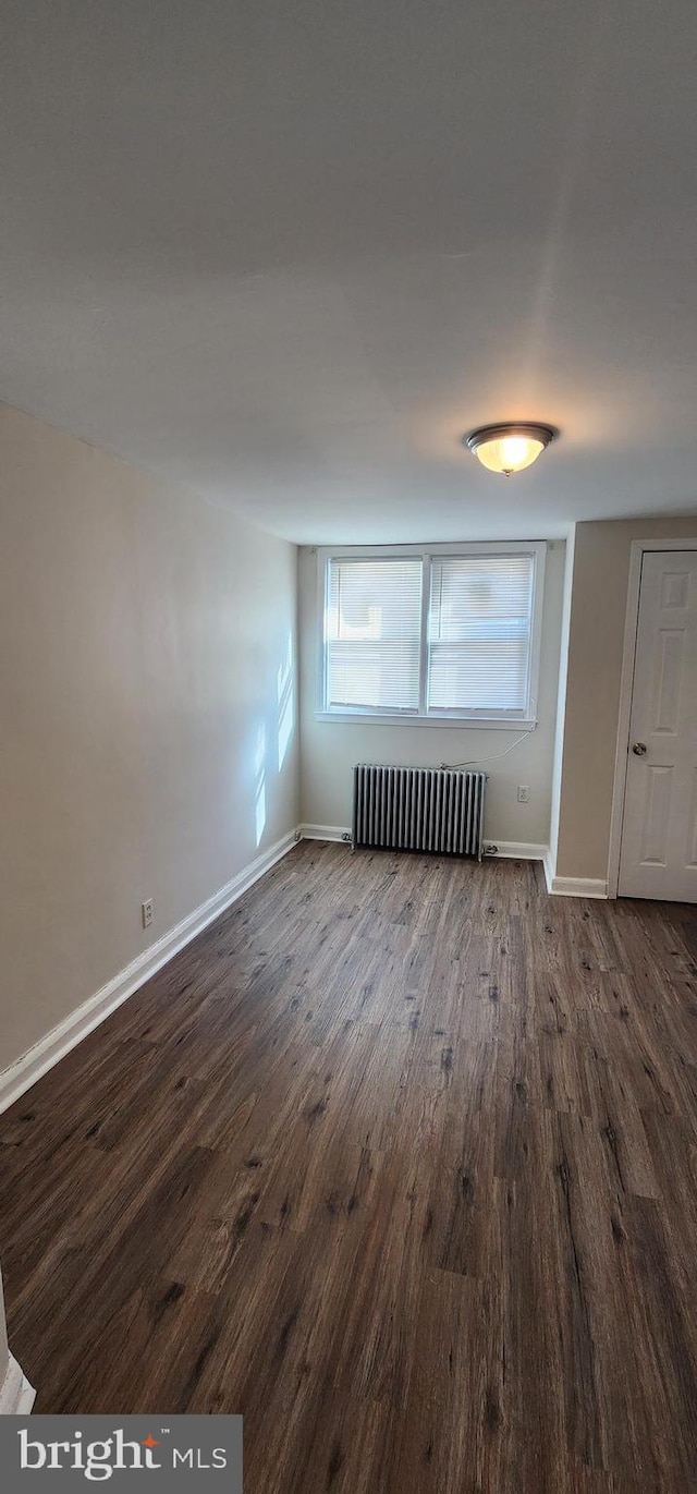 unfurnished room with radiator and dark wood-type flooring