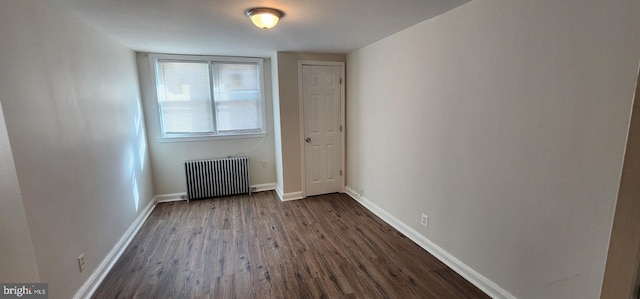 empty room with radiator and dark hardwood / wood-style floors