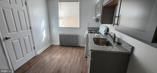 kitchen featuring stone countertops, radiator, dark hardwood / wood-style floors, white gas range, and sink