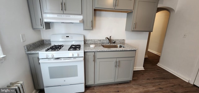 kitchen with light stone counters, white gas range, sink, and gray cabinetry