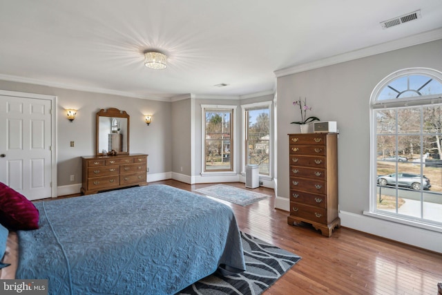 bedroom featuring multiple windows, hardwood / wood-style flooring, and ornamental molding