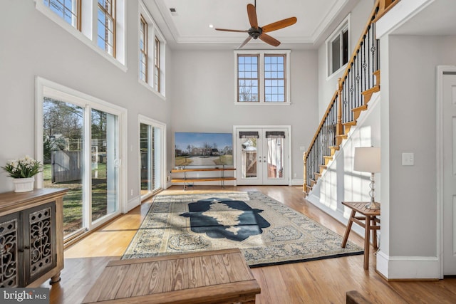 entrance foyer with light hardwood / wood-style floors, ornamental molding, french doors, and a high ceiling