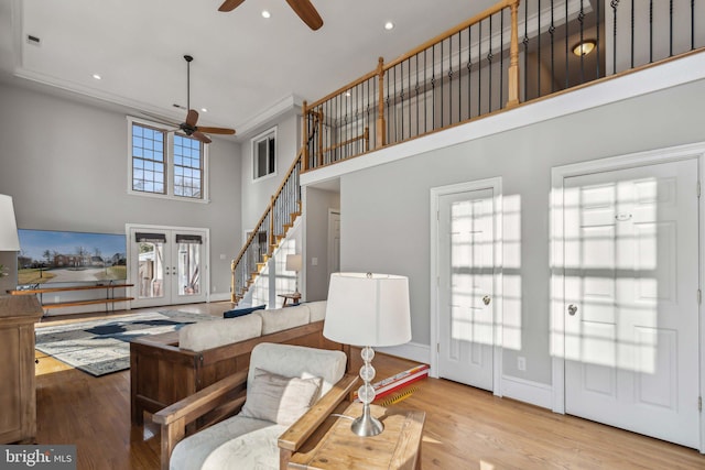 living room featuring french doors, ceiling fan, a towering ceiling, and light wood-type flooring