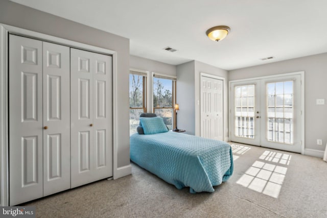 bedroom featuring two closets, access to outside, french doors, and carpet flooring