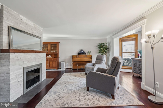 living room with dark hardwood / wood-style flooring, a stone fireplace, crown molding, and a chandelier