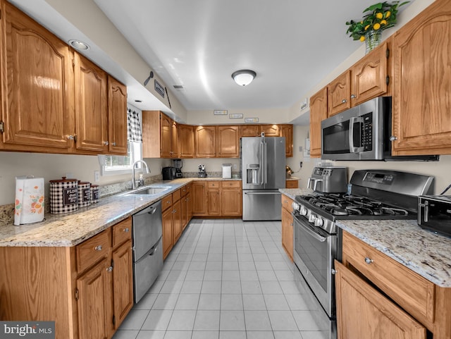 kitchen with light stone counters, sink, light tile patterned floors, and stainless steel appliances