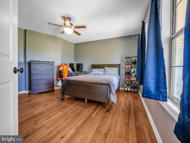 bedroom with ceiling fan, a textured ceiling, and light hardwood / wood-style floors