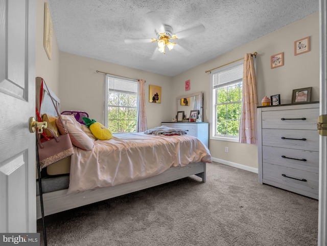 bedroom with dark colored carpet, ceiling fan, and a textured ceiling