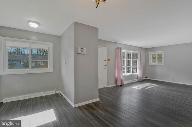 unfurnished room with dark hardwood / wood-style flooring and a baseboard heating unit