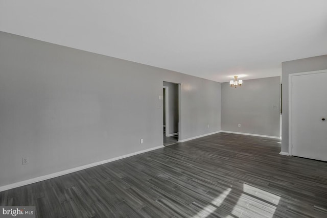 unfurnished room featuring an inviting chandelier and dark hardwood / wood-style floors