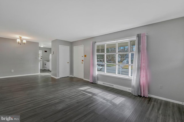 unfurnished living room with a notable chandelier and dark hardwood / wood-style floors