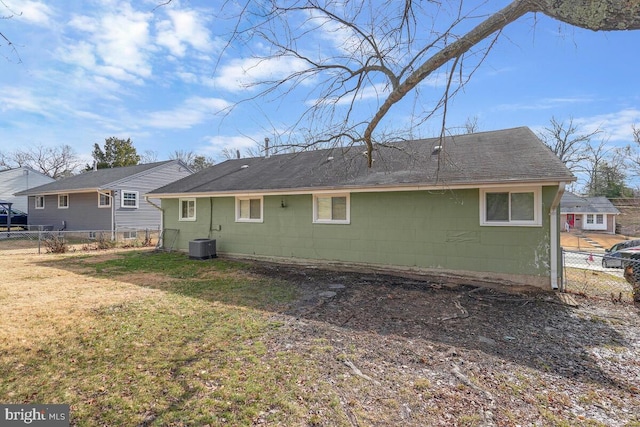 rear view of house with central AC unit and a yard