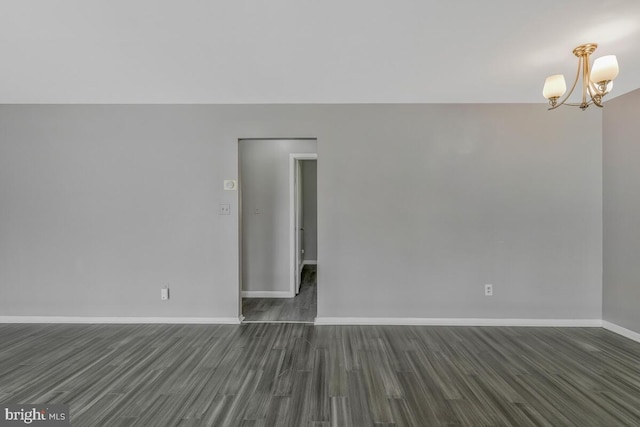 spare room with an inviting chandelier and dark hardwood / wood-style floors