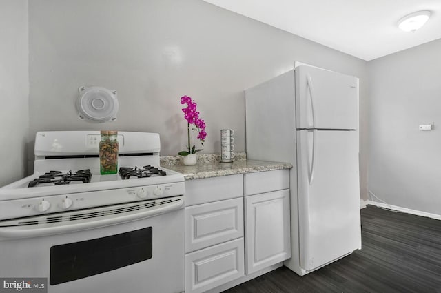 kitchen with white appliances, dark hardwood / wood-style floors, and white cabinets