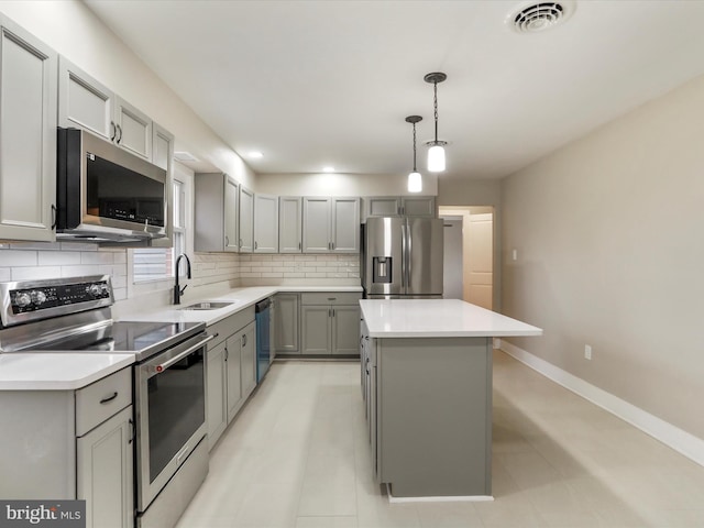 kitchen featuring a kitchen island, sink, decorative backsplash, hanging light fixtures, and stainless steel appliances