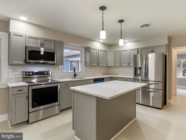 kitchen with a kitchen island, appliances with stainless steel finishes, sink, and gray cabinetry