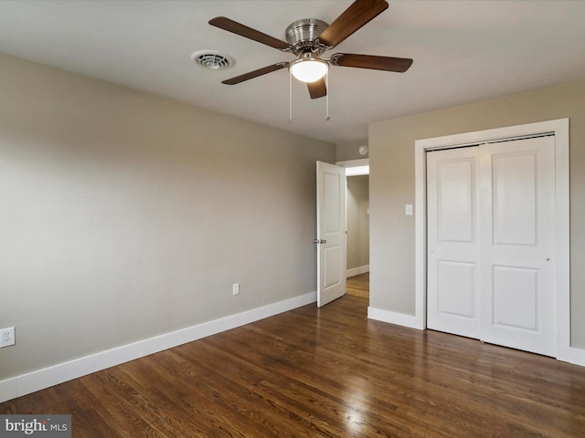 unfurnished bedroom with ceiling fan, dark hardwood / wood-style flooring, and a closet