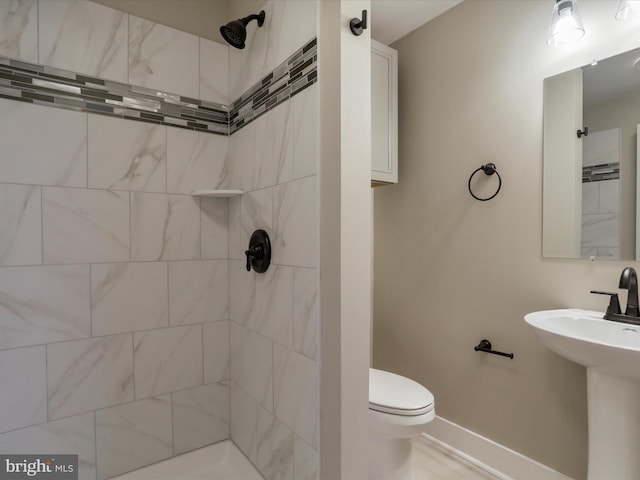 bathroom with sink, toilet, and tiled shower