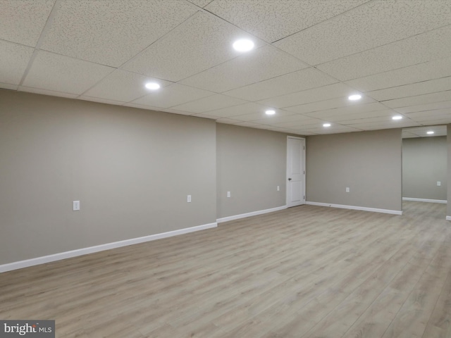 basement featuring a drop ceiling and light hardwood / wood-style flooring