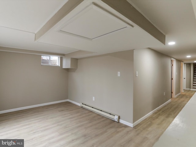 basement with a baseboard radiator and light hardwood / wood-style flooring