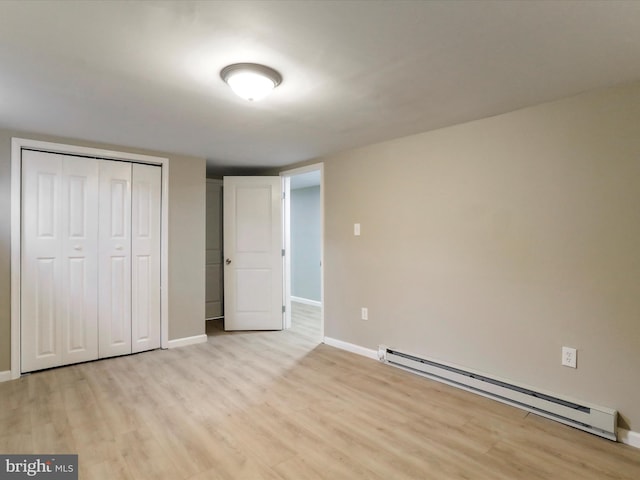 unfurnished bedroom with baseboard heating, a closet, and light wood-type flooring