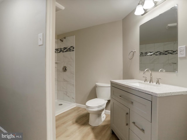 bathroom featuring vanity, toilet, hardwood / wood-style floors, and a tile shower