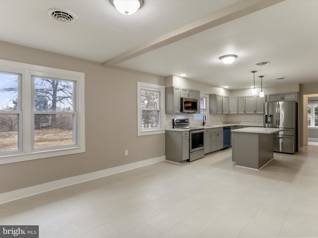 kitchen featuring sink, appliances with stainless steel finishes, gray cabinets, a kitchen island, and pendant lighting