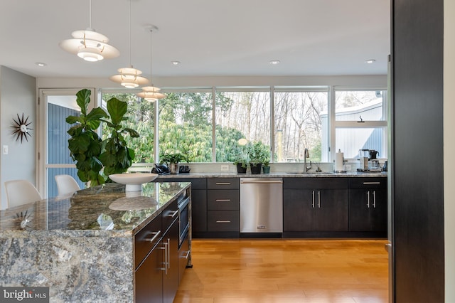 kitchen featuring stainless steel dishwasher, light stone countertops, light hardwood / wood-style floors, and hanging light fixtures