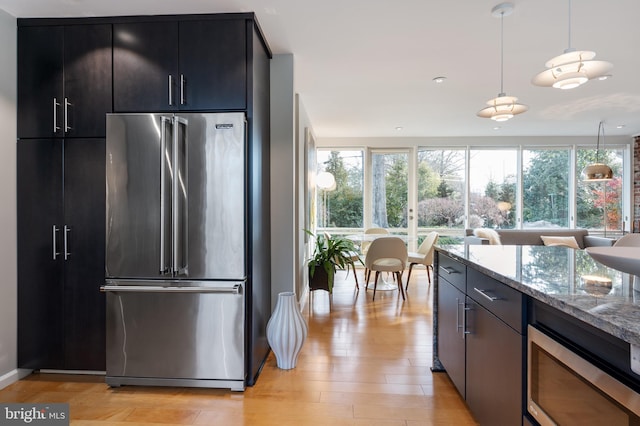 kitchen featuring decorative light fixtures, appliances with stainless steel finishes, plenty of natural light, light stone countertops, and light hardwood / wood-style floors