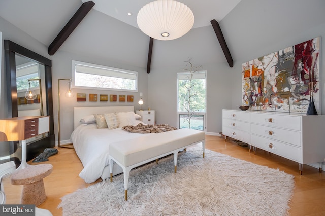 bedroom with lofted ceiling with beams and light wood-type flooring