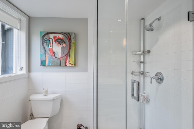 bathroom with tiled shower, toilet, and tile walls