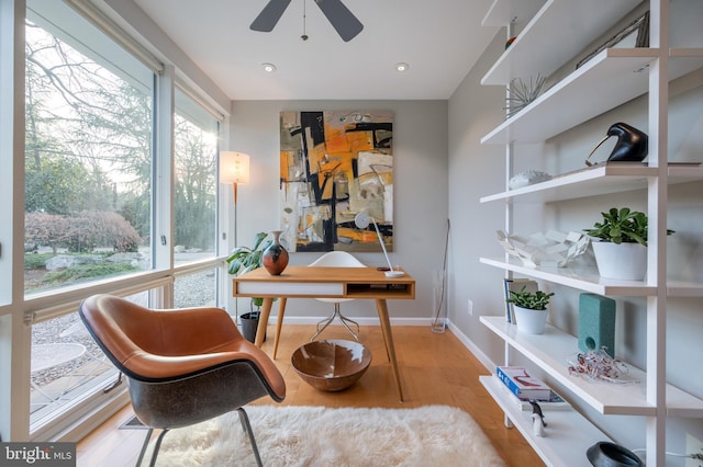 home office with light hardwood / wood-style floors and ceiling fan