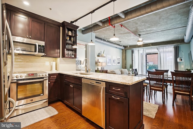 kitchen with stainless steel appliances, decorative light fixtures, kitchen peninsula, and sink