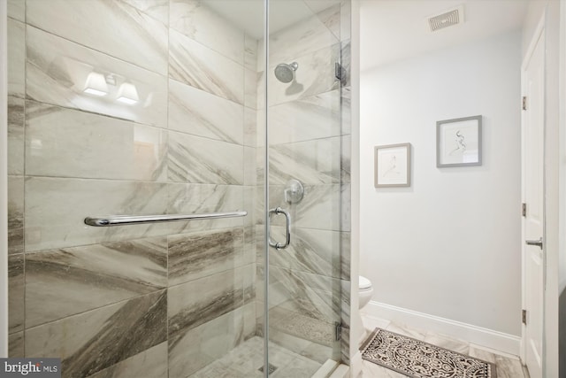 bathroom with a shower with shower door and toilet